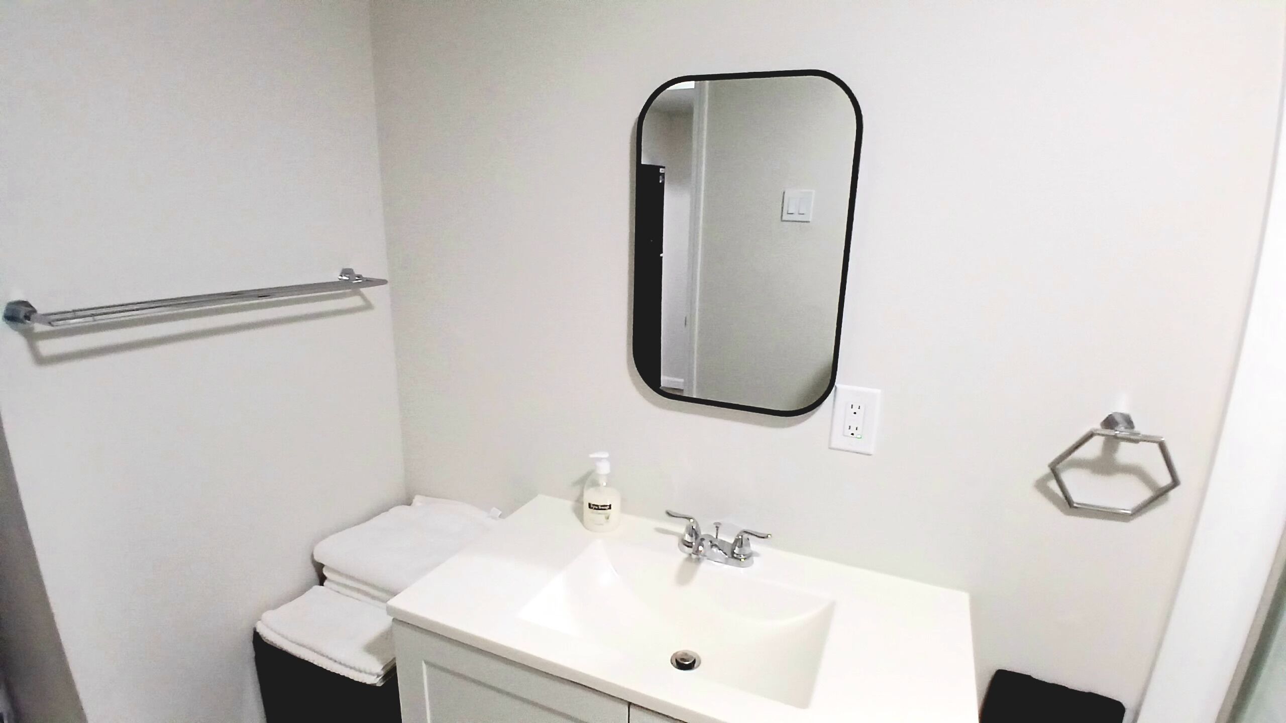 A bathroom with a white sink, a mirror, a towel rack, and a toilet.