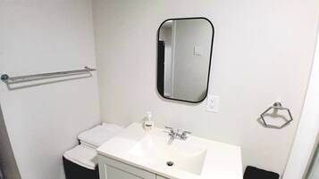 A bathroom with a white sink, a mirror, a towel rack, and a toilet.