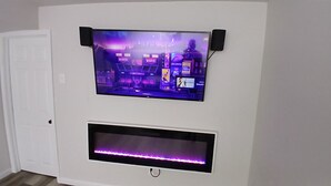 A wall-mounted TV with a purple-lit screen displaying a cityscape.
