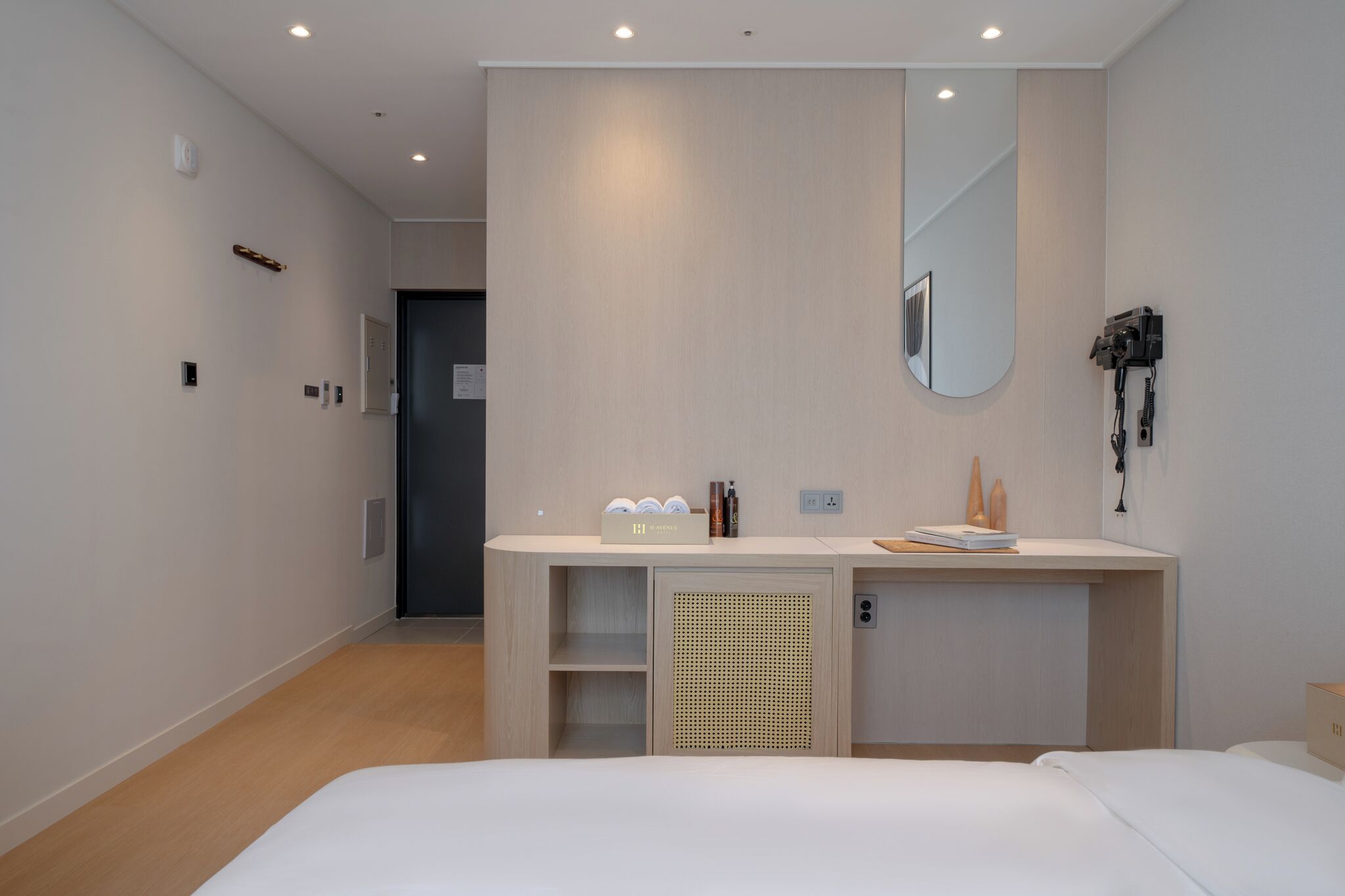 Et moderne hotelværelse med en seng, et skrivebord med et spejl og et lille tekøkken.