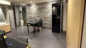 A modern kitchen with a dining area, a black table, and a brick wall.