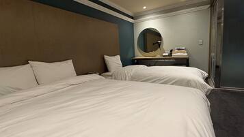 Habitación de hotel con dos camas, un espejo redondo, una mesita con lámpara y una puerta corredera.