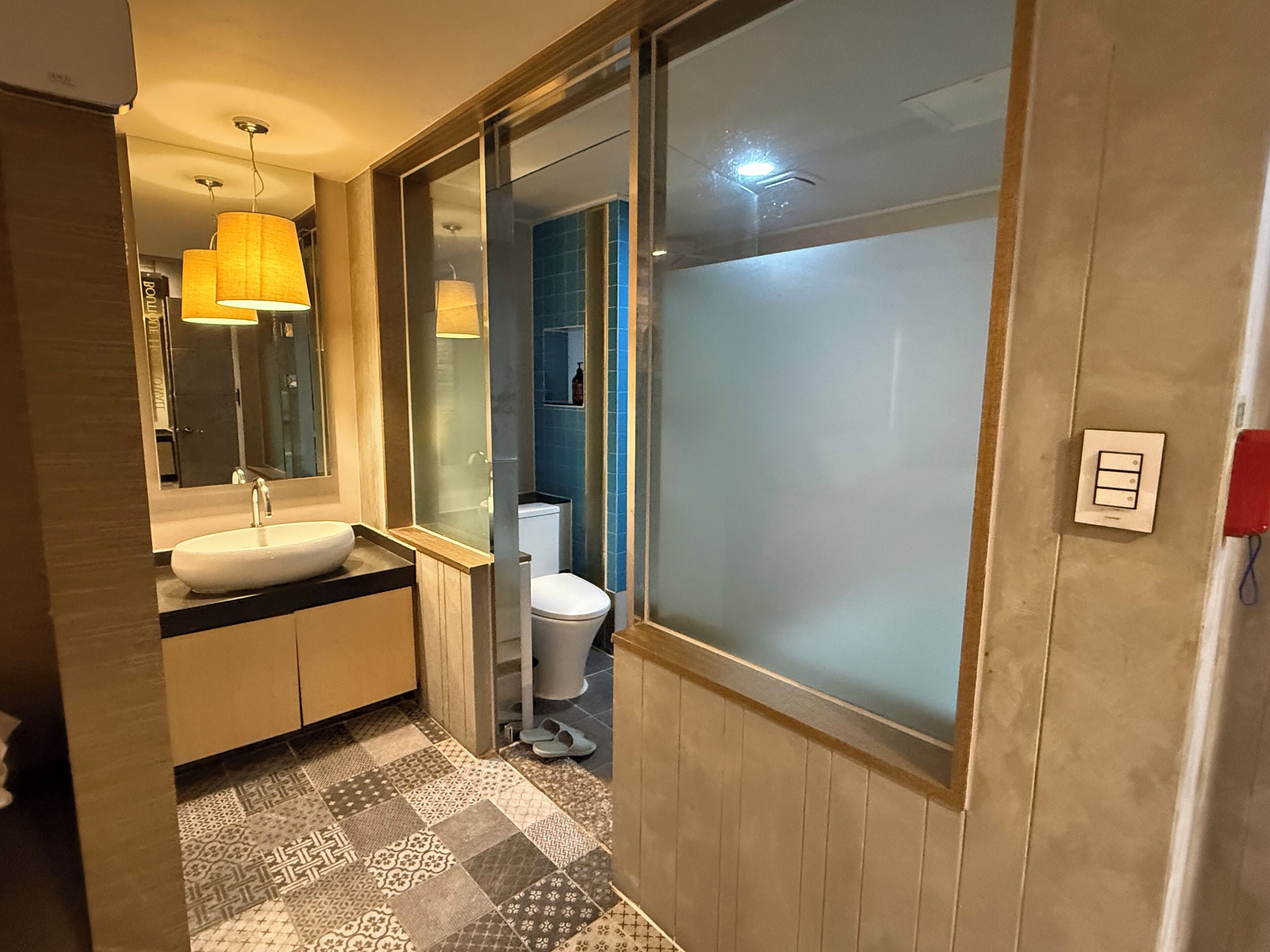 A bathroom with a sink, mirror, toilet, and a shower area.