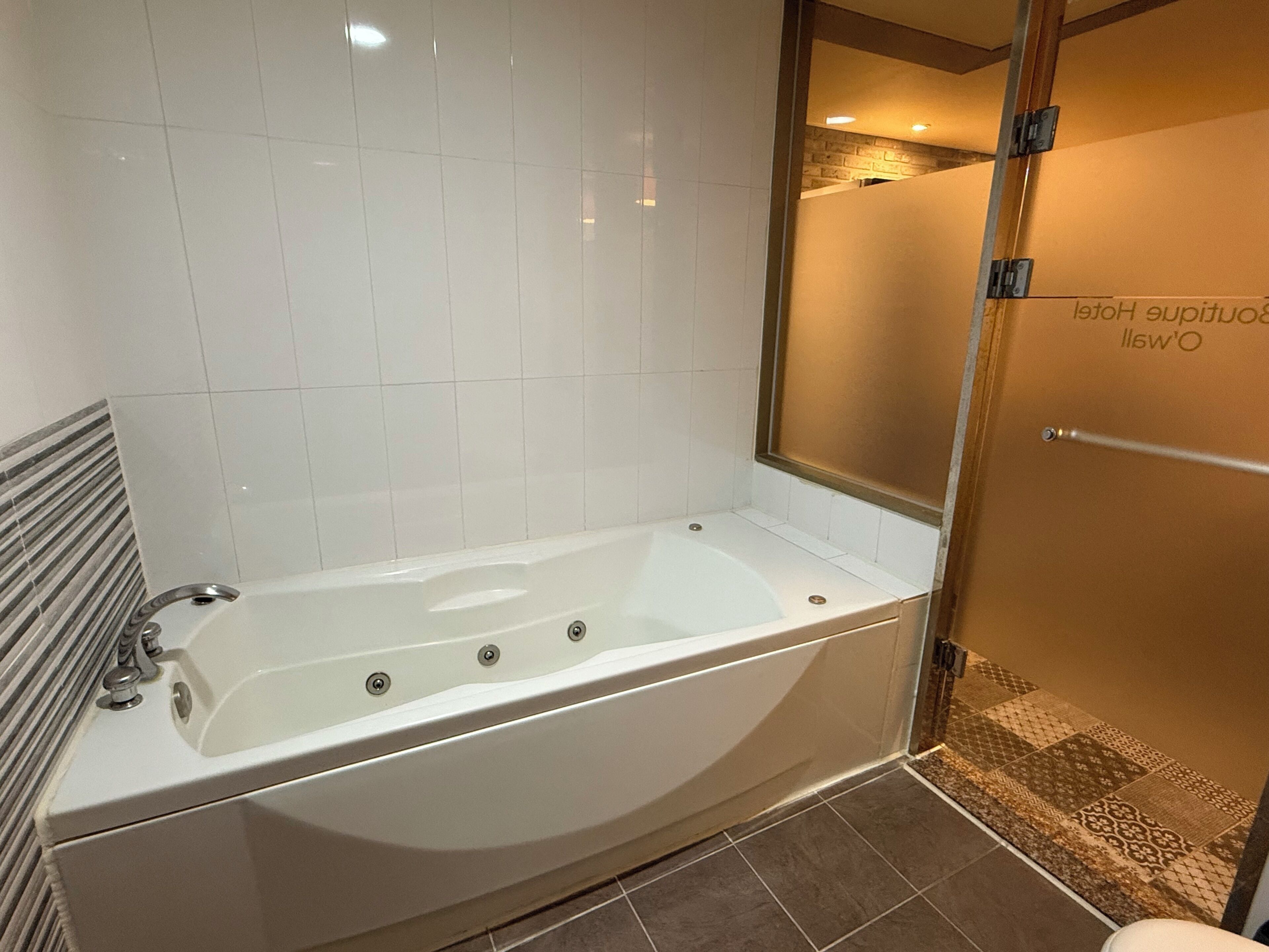 Un baño moderno con una bañera independiente, cabina de ducha con mampara de vidrio y suelo de baldosas.