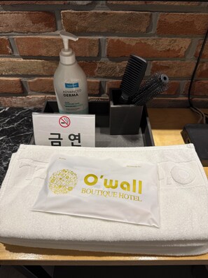A bathroom set with toiletries, a towel, and a sign with Korean text.