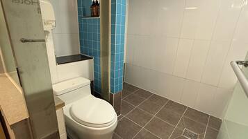 A bathroom with a toilet, a shower, and a sink.