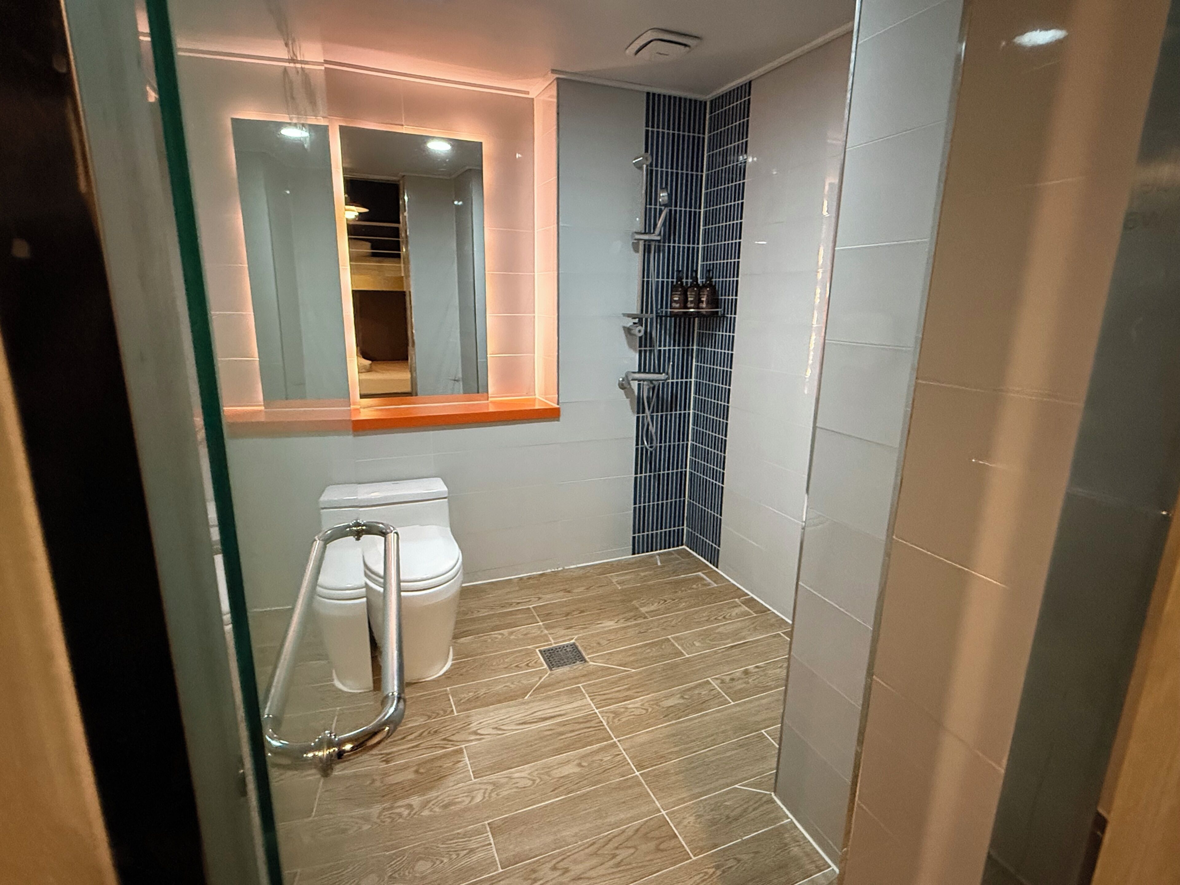 A small, modern bathroom with a glass shower enclosure, a toilet, and a sink.
