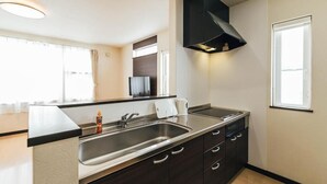 Cozinha moderna com pia de aço inoxidável, armários escuros e coifa preta.