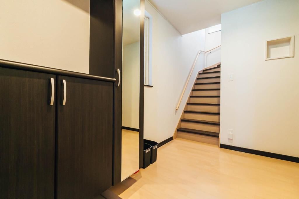 A hallway with a dark wooden wardrobe, a staircase, and a light-colored floor.