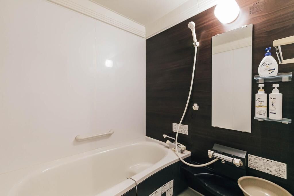 A modern bathroom with a bathtub, a shower, and a sink. There are toiletries on the wall and a mirror above the sink.