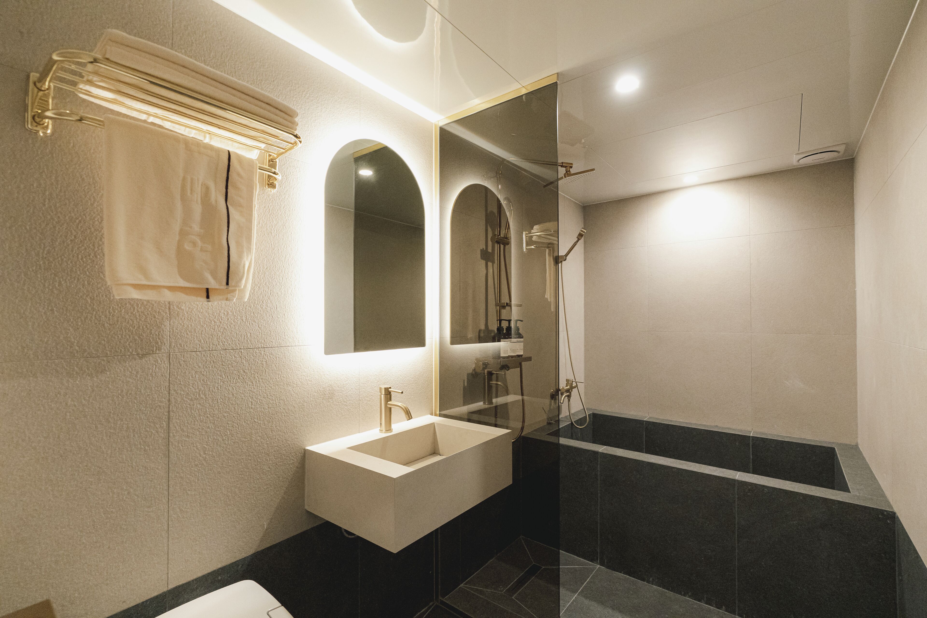 A modern bathroom with a large mirror, a sink, and a bathtub.