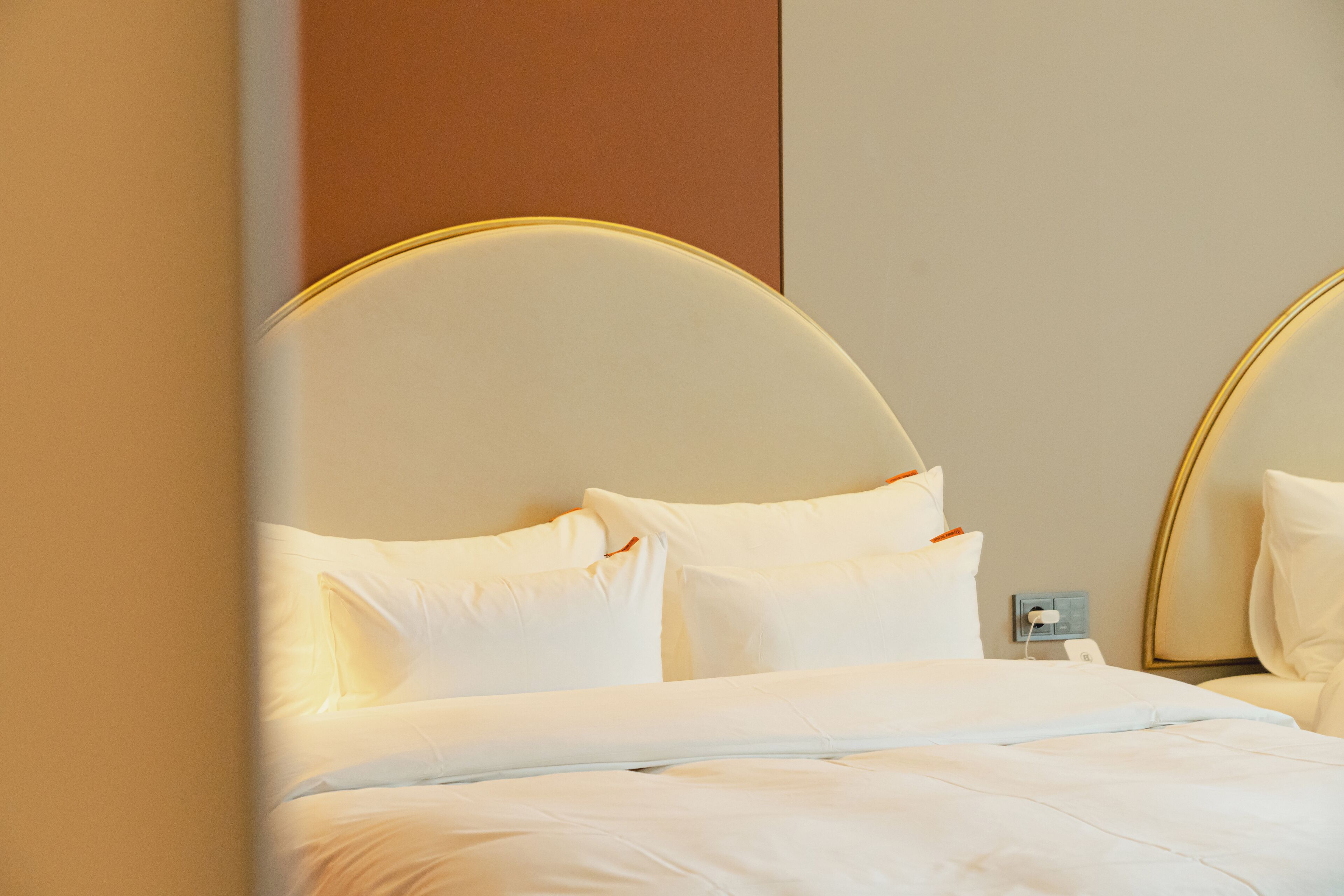 Habitación de hotel con una cama, ropa de cama blanca y un cabecero moderno de diseño circular.