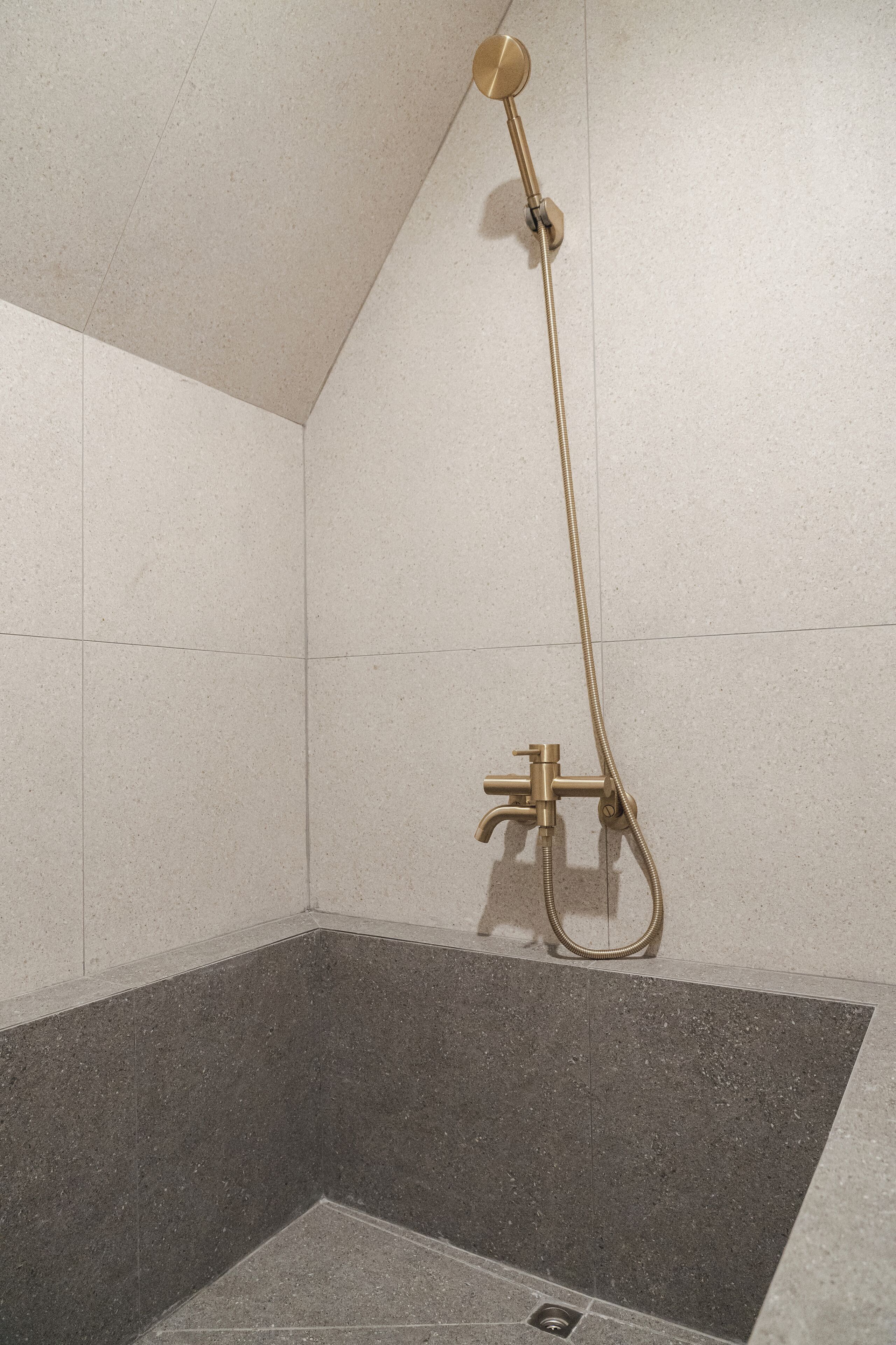 Un espace douche équipé d’un pommeau de douche à main et d’un robinet mural.