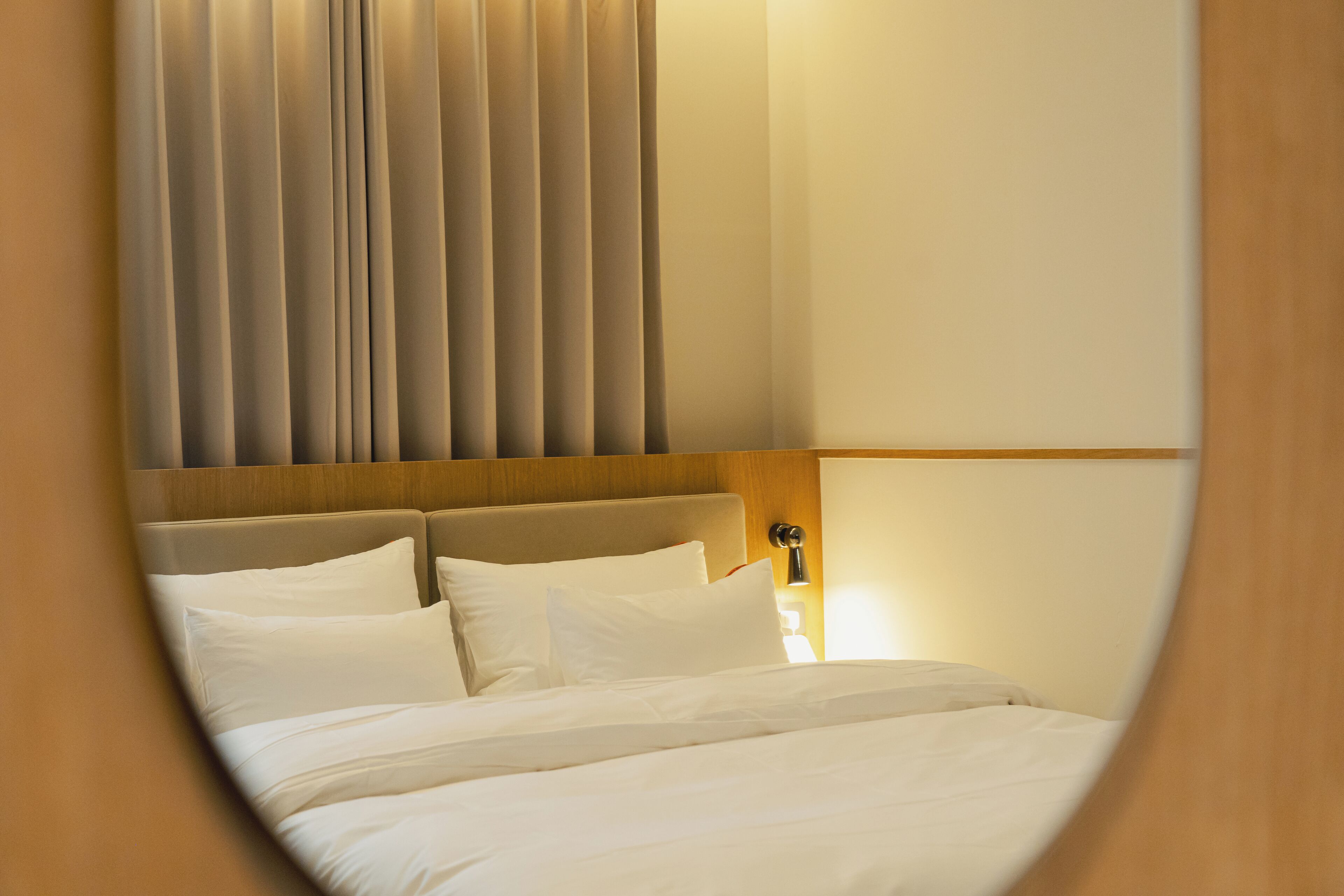 Une chambre d’hôtel avec un lit, des rideaux et une table de chevet avec une lampe.