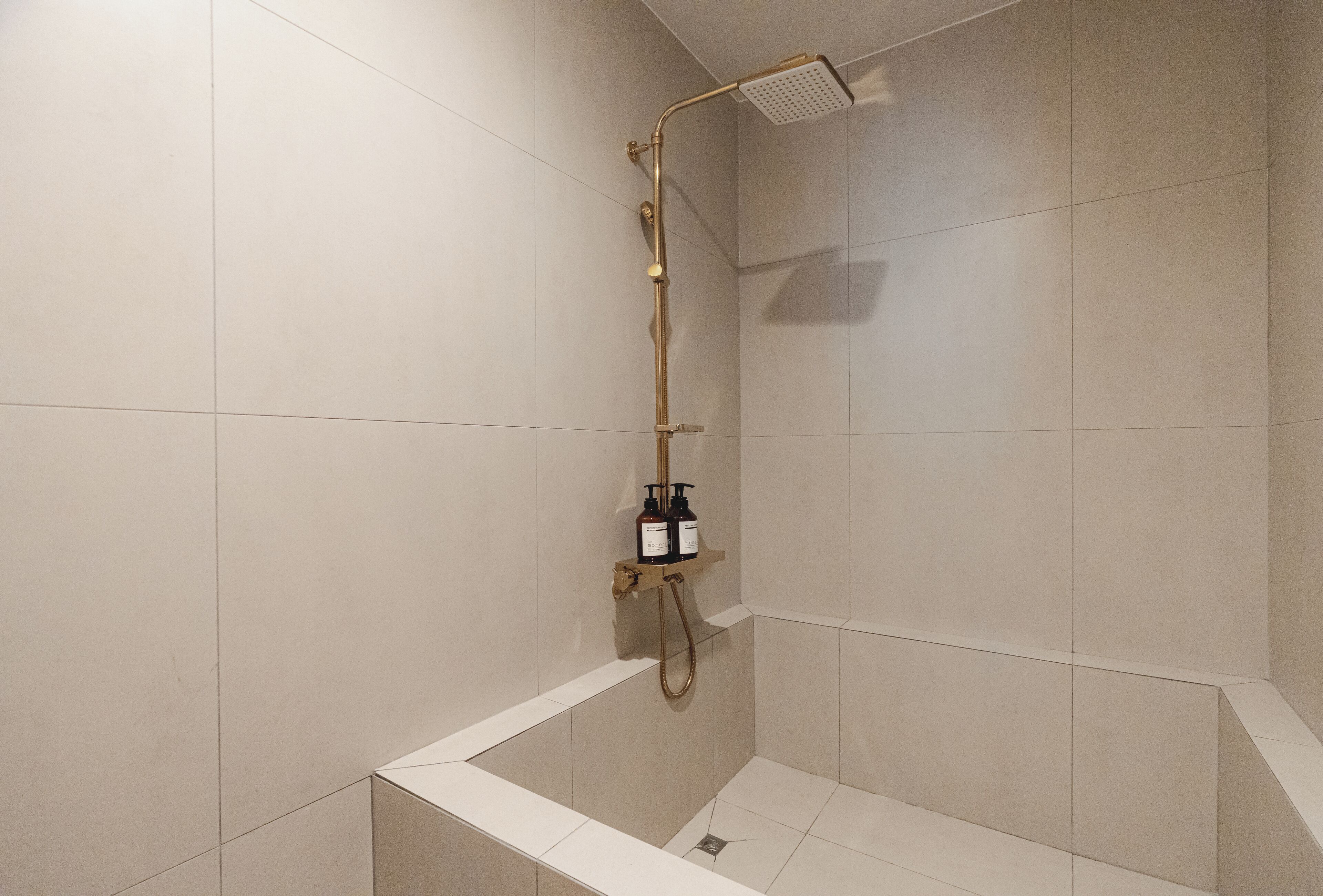 A modern shower with a handheld showerhead and a wall-mounted control panel.