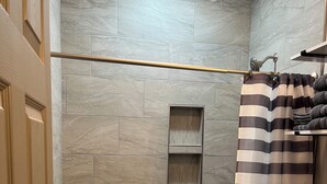 A bathroom with a shower, toilet, and a towel rack.
