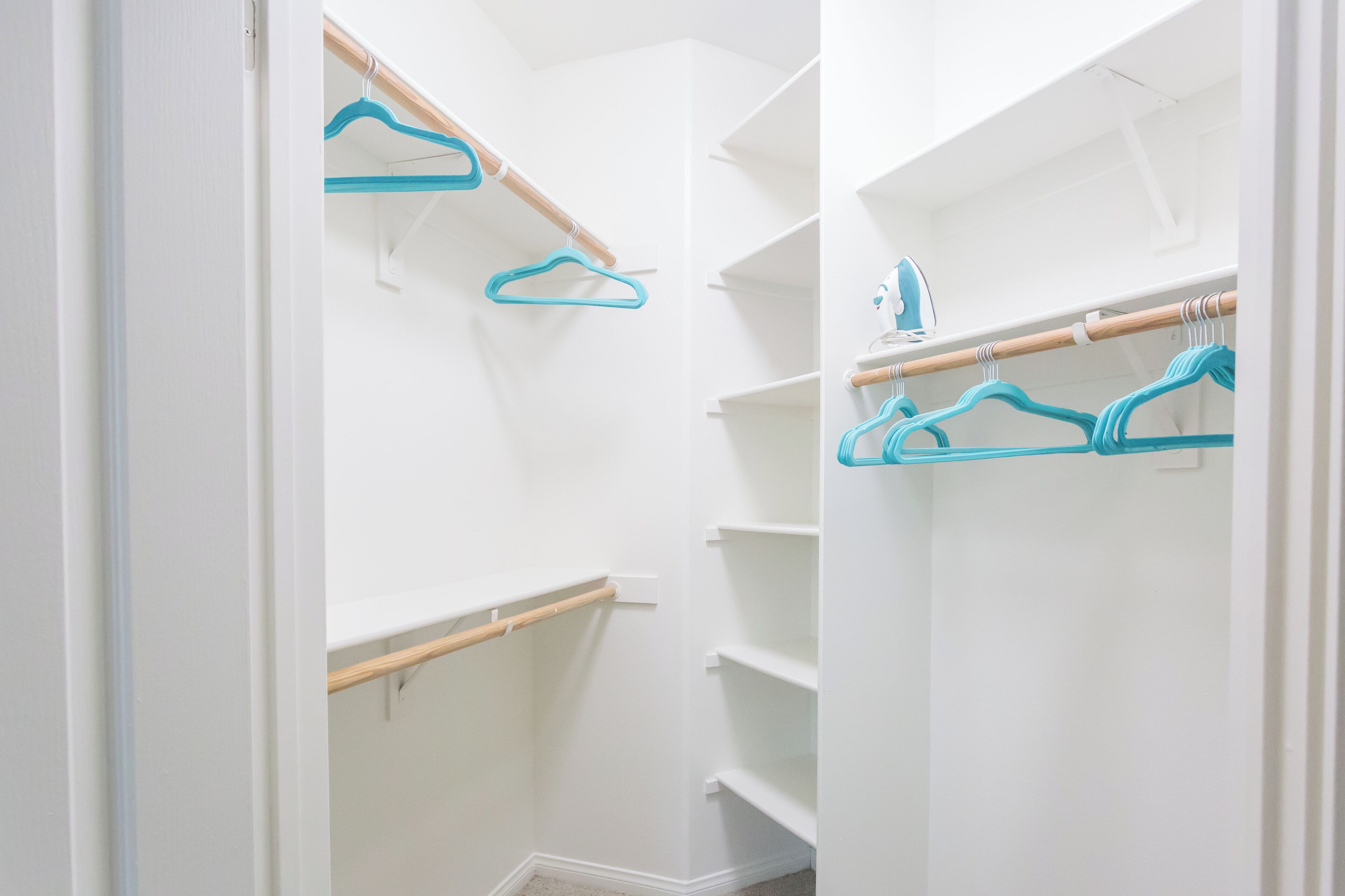 A walk-in closet with open shelves and a wooden rod for hanging clothes.