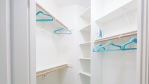 Un vestidor amplio con estantes abiertos y una barra de madera para colgar ropa.