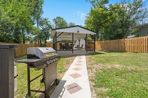 A backyard with a barbecue grill, a covered patio, and a wooden fence. - Free Attraction Tickets_Walk to Branson Landing & Historic Downtown Branson (Branson)