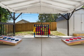 An outdoor patio with a wooden fence, a colorful board game, and a covered area.