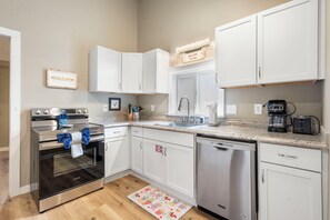 A modern kitchen with white cabinets, stainless steel appliances, and a coffee maker.