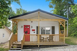 Ein kleines Blockhaus mit Veranda, roter Tür und Briefkasten.