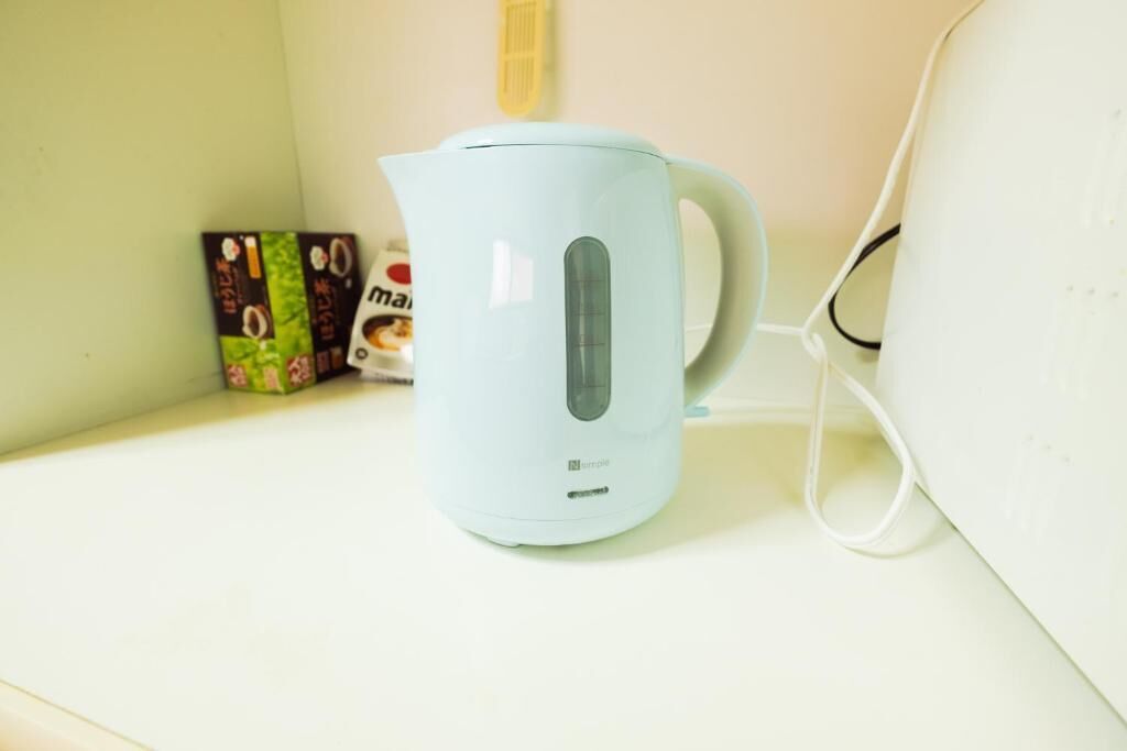 A light blue electric kettle on a white countertop, connected to a power outlet.