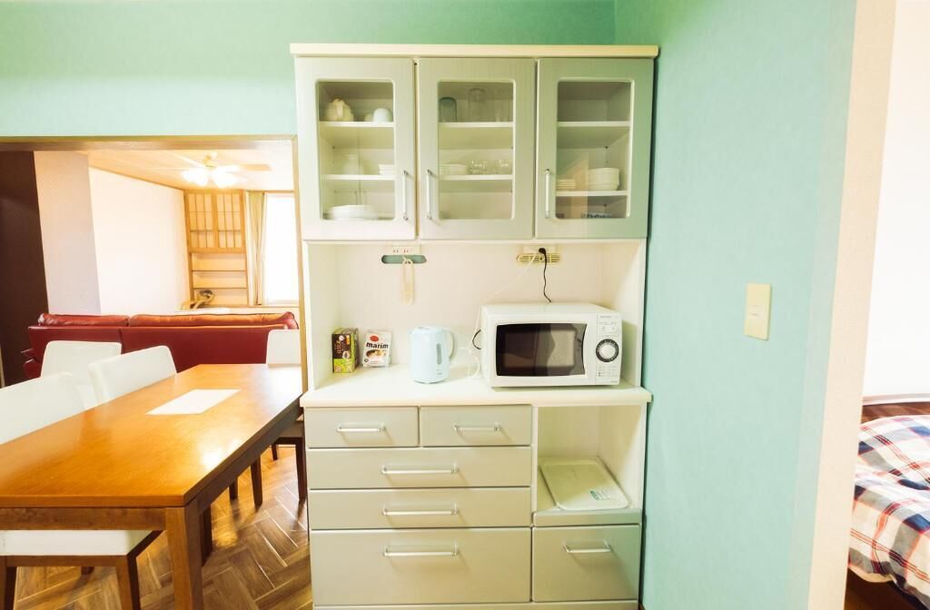 A compact kitchen with a microwave, a coffee maker, and a cabinet with glass doors.