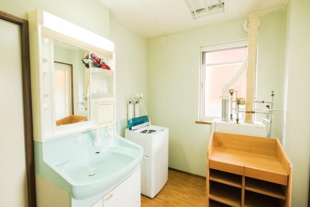 A small, well-lit bathroom with a sink, mirror, and a window.