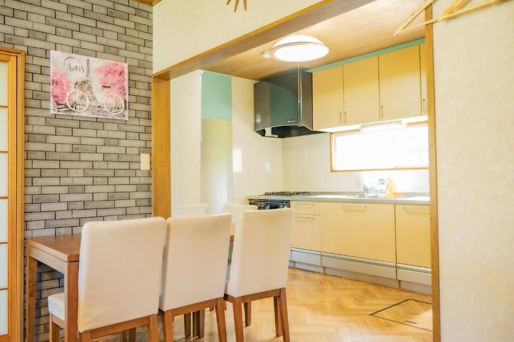 A kitchen with a brick wall, a painting of the Eiffel Tower, and a dining area with a table and chairs.