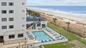 Un hotel con piscina, sillas de descanso y vista a la playa.