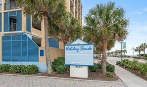 Un panneau indiquant l’emplacement de l’hôtel Holiday Sands South Beach, avec une entrée pour le stationnement et un bureau de location.