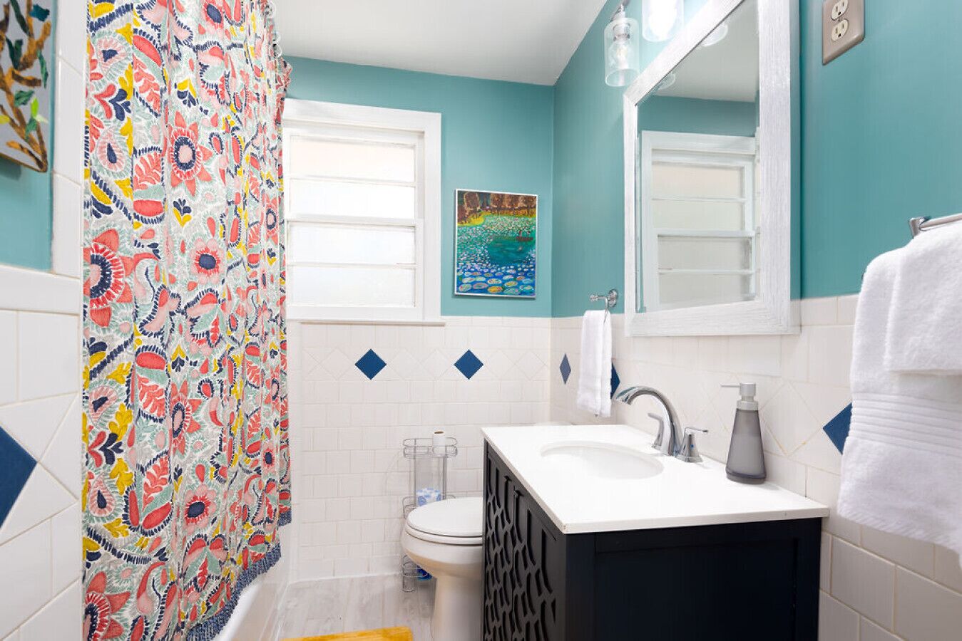 Une salle de bain avec un rideau de douche coloré, un lavabo avec un miroir et des toilettes.