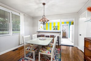 A dining area with a table and chairs, a hanging light fixture, and a colorful rug. - The Cottage Near Columbus` Best Shopping & Dining! (Columbus)