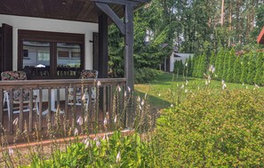 A covered outdoor area with a wooden deck, a seating arrangement, and a well-maintained garden with various plants and flowers.
