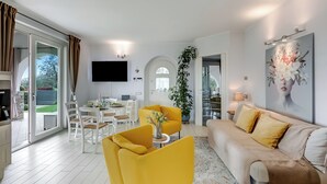 Una sala moderna con sofá, sillón amarillo y zona de comedor.