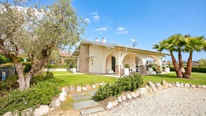Una casa moderna con porche cubierto, paredes de piedra y césped cuidado.