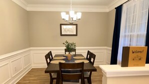 A dining room with a wooden table, six chairs, a chandelier, a framed artwork, and a welcome sign. - Home the way you need it. (Lexington)