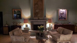 A traditional living room with two armchairs, a fireplace, a mirror, and a painting on the wall. - Casa del Roble 2 Residence (Cuernavaca)