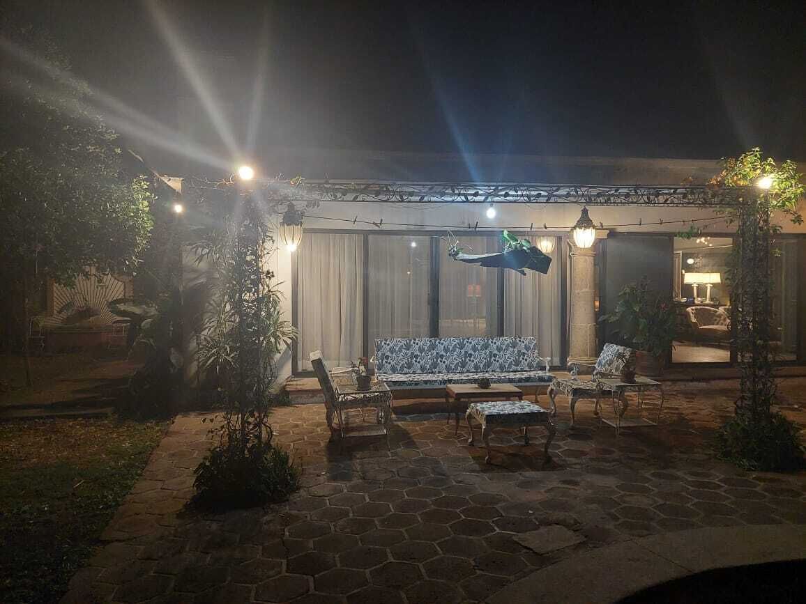 Un espacio de patio al aire libre con un sofá, sillas y una mecedora colgante.