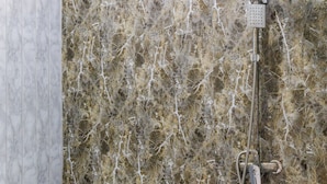 Une salle de bain avec un mur en marbre, des toilettes blanches et une douche.