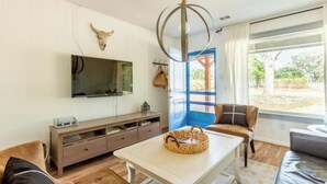 Een woonkamer met een aan de muur bevestigde televisie, een houten kast, een witte tafel en een bruine leren bank.