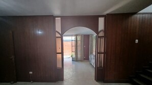 A hallway with wooden doors leading to a room.