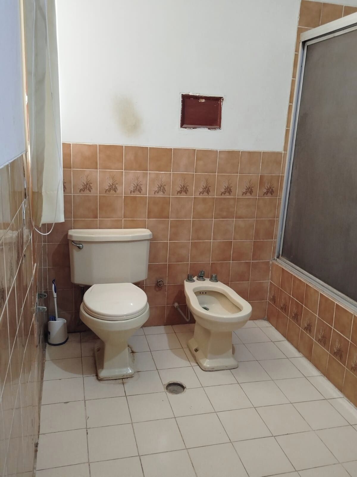 A bathroom with a toilet, bidet, and a small window.