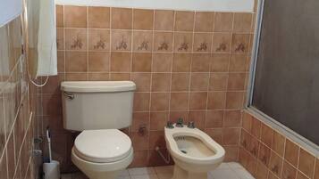 A bathroom with a toilet, bidet, and a small window.