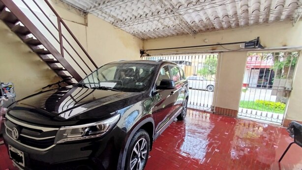 A black SUV parked in a garage with a tiled floor and a staircase.