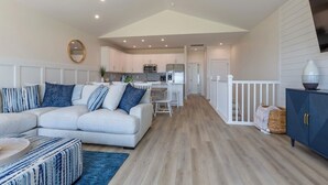 A modern living room with a sectional sofa, a dining area, and a kitchen in the background. - 4bedroom,5bed,4bath, elevator, ocean views and golf cart (Surf City)
