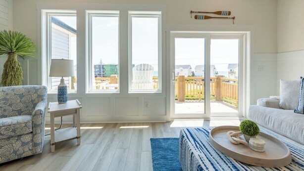 A spacious living room with a large sliding glass door leading to a balcony, a patterned sofa, a small side table, and a decorative tray. - 4bedroom,5bed,4bath, elevator, ocean views and golf cart (Surf City)