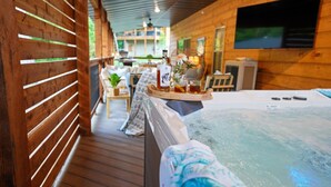 L’intérieur d’un chalet en bois comprend un jacuzzi, des lambris en bois, un téléviseur et un coin repas.