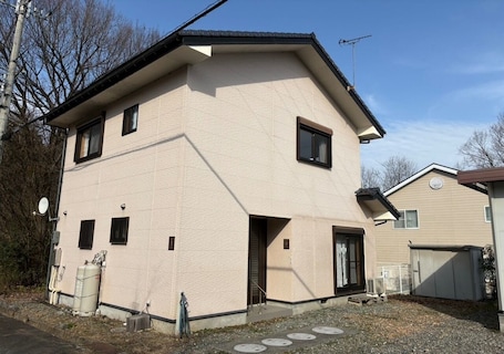 A two-story building with a beige exterior, a small front porch, and a satellite dish.